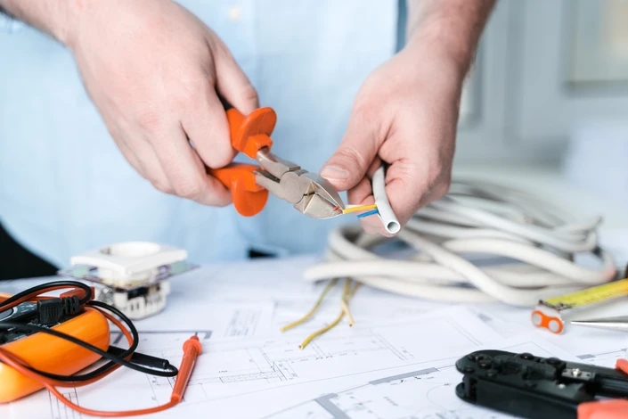 Un électricien travaille sur un plan technique avec des câbles électriques multicolores